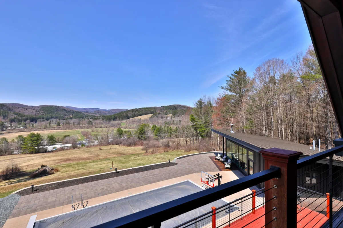 A wide-angle view of Casita Alta's modern architecture set against an expansive natural landscape. The scene includes a stylish swimming pool area, inviting outdoor spaces, and the surrounding hills, evoking both a sense of privacy and connection to the region's scenic beauty.