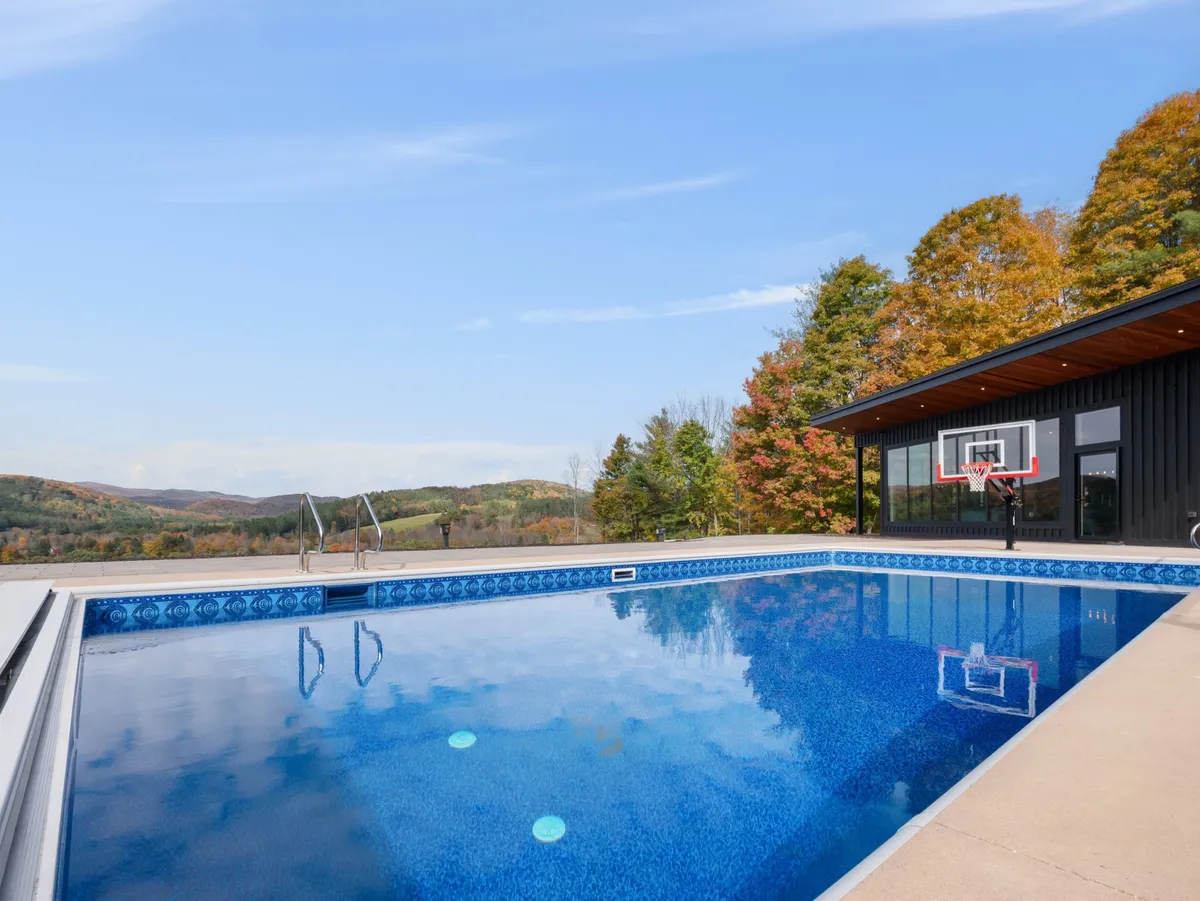 The image showcases the exterior of Casita Alta, with a sparkling heated saltwater pool in the foreground, a basketball hoop nearby, and sweeping mountain views stretching into the distance. The serene landscape invites relaxation and outdoor fun, ideal for both active and leisurely experiences.